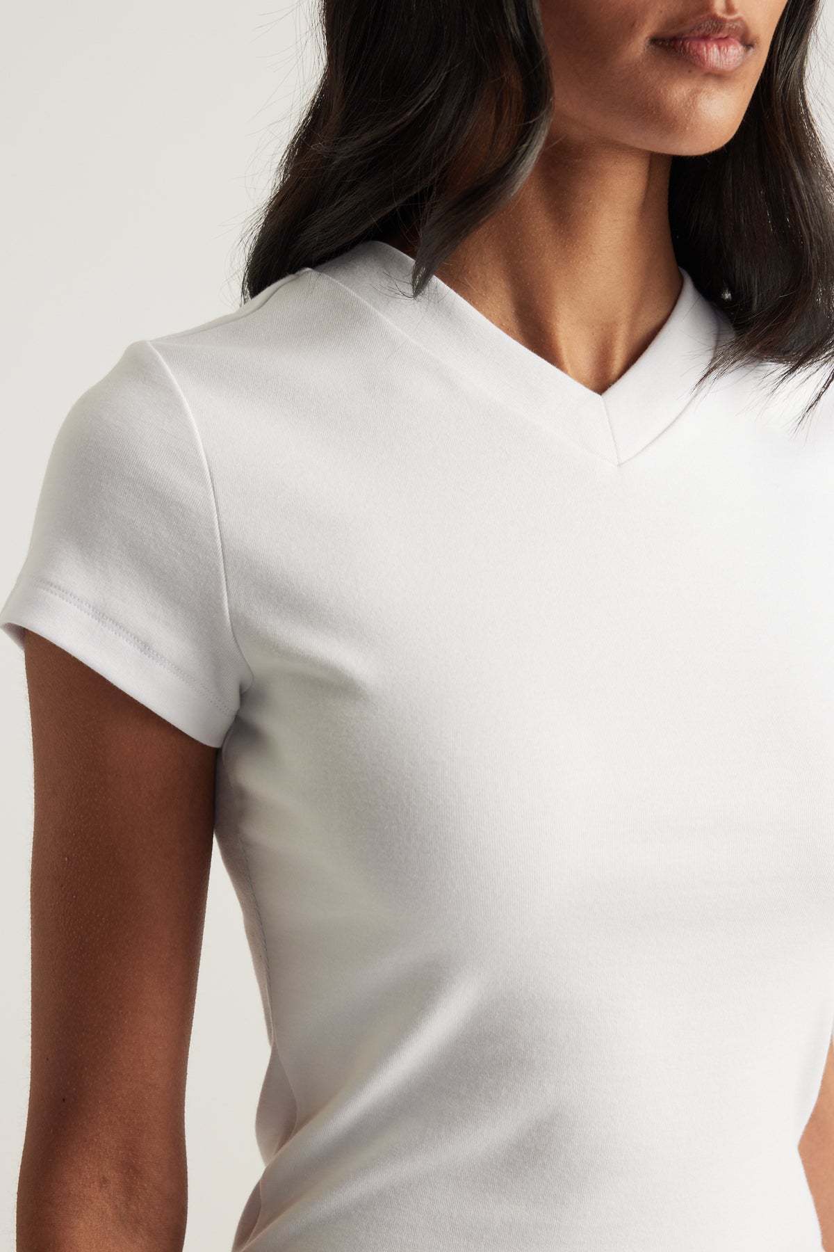 Woman wearing a white fitted short sleeve tee with a V-neckline