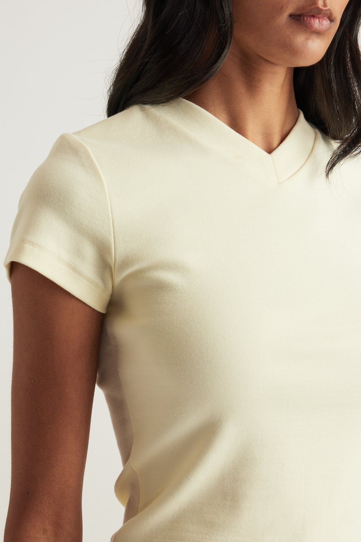 Woman wearing a cream short sleeve V neck tee with a fitted silhouette