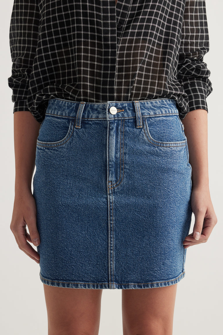 Woman wearing a high rise blue denim mini skirt with a checked shirt