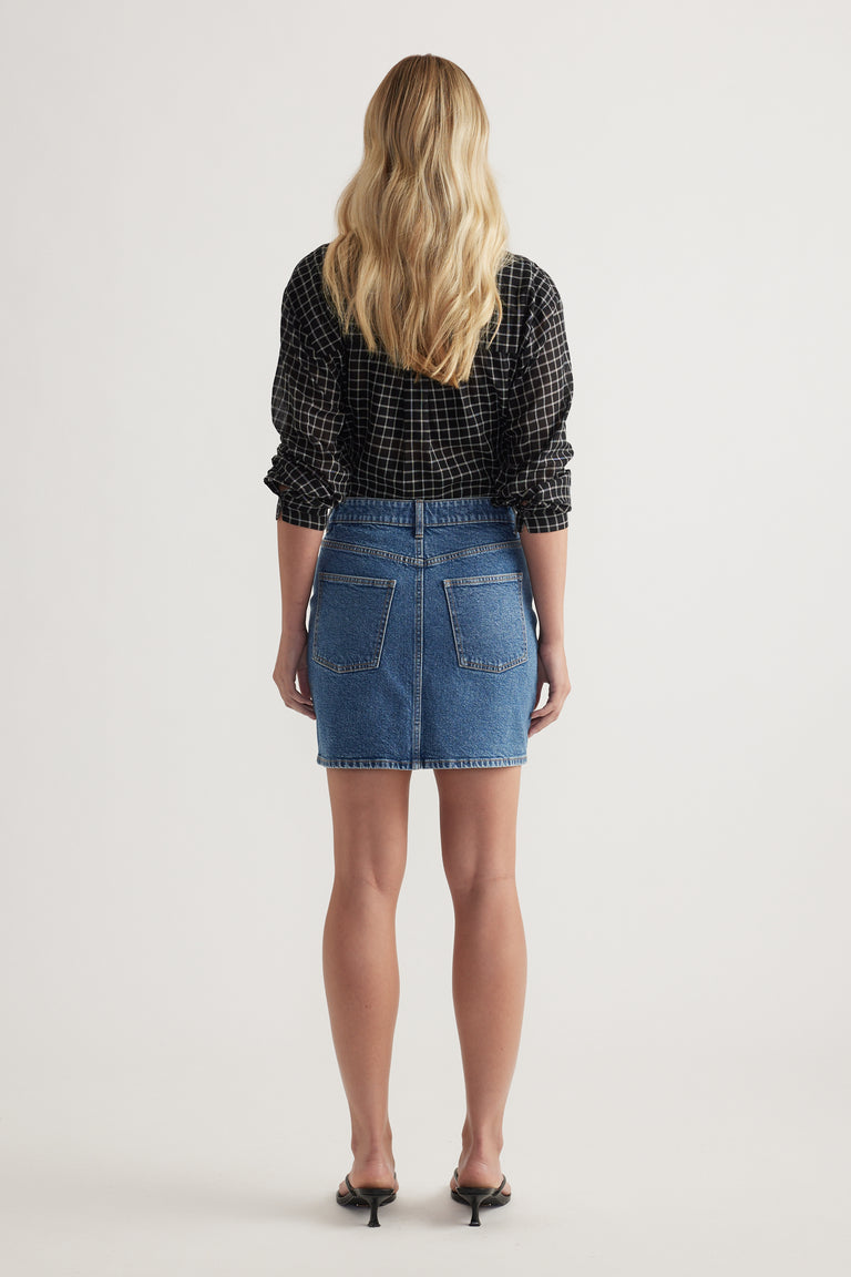 Back view of a woman wearing a high rise denim mini skirt with a black checked shirt