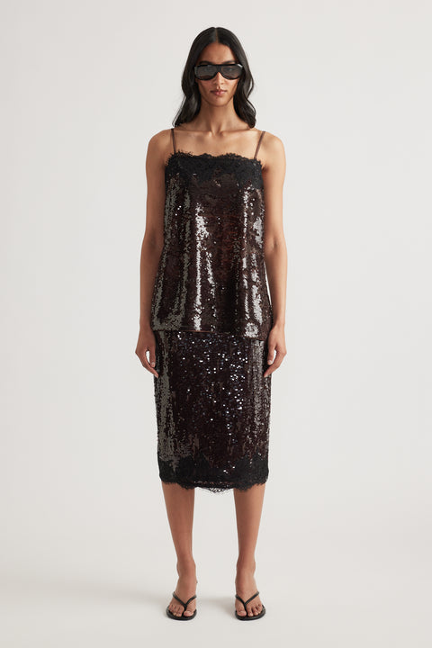 Woman wearing a dark sequin cami with a matching midi skirt and sunglasses