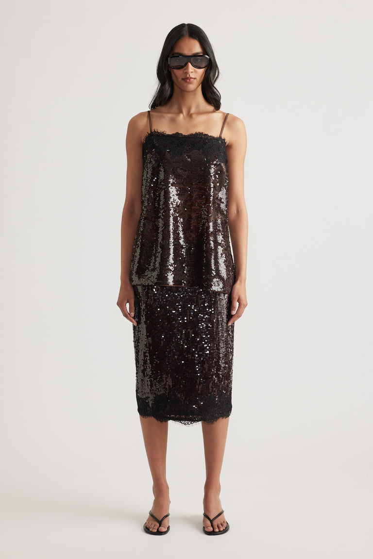 Woman wearing a dark sequin cami with a matching midi skirt and sunglasses