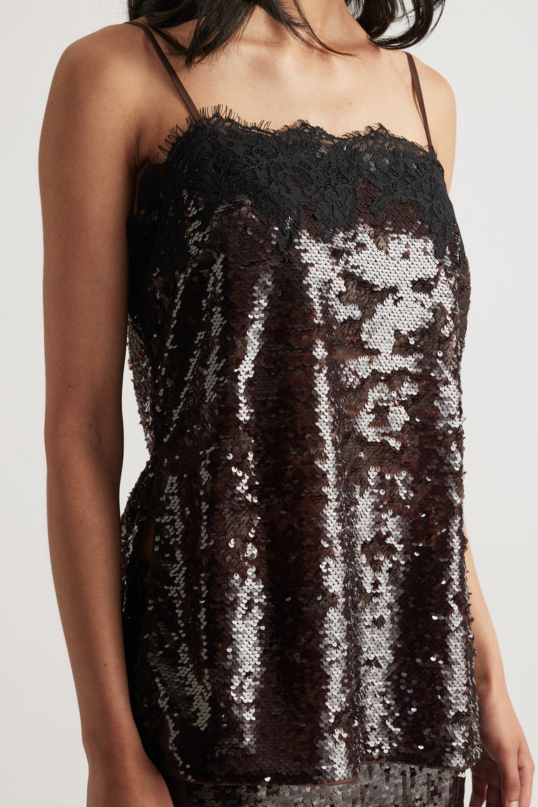 Woman wearing a black sequin cami top with thin straps, square neckline and lace trim