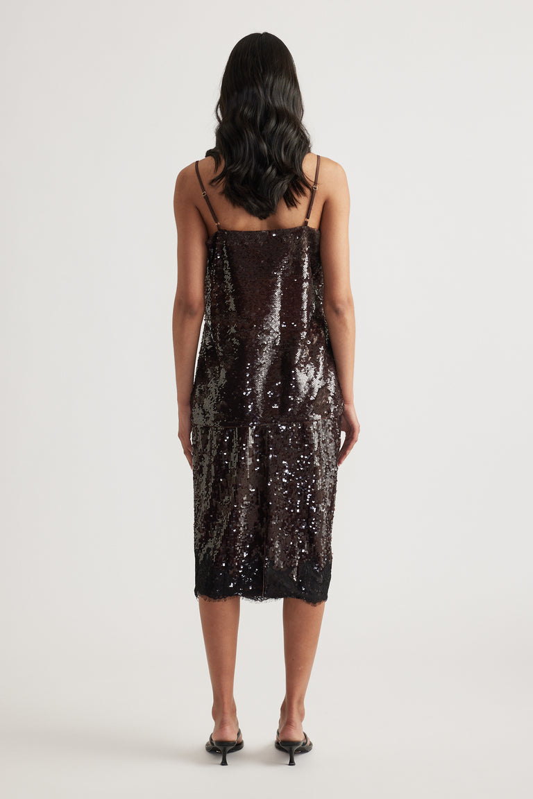 Woman seen from behind wearing a black sequin cami with thin straps and a matching midi skirt