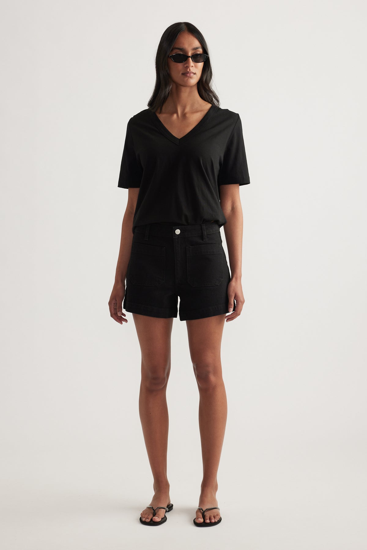 Woman wearing a black tee and high rise denim shorts with front patch pockets