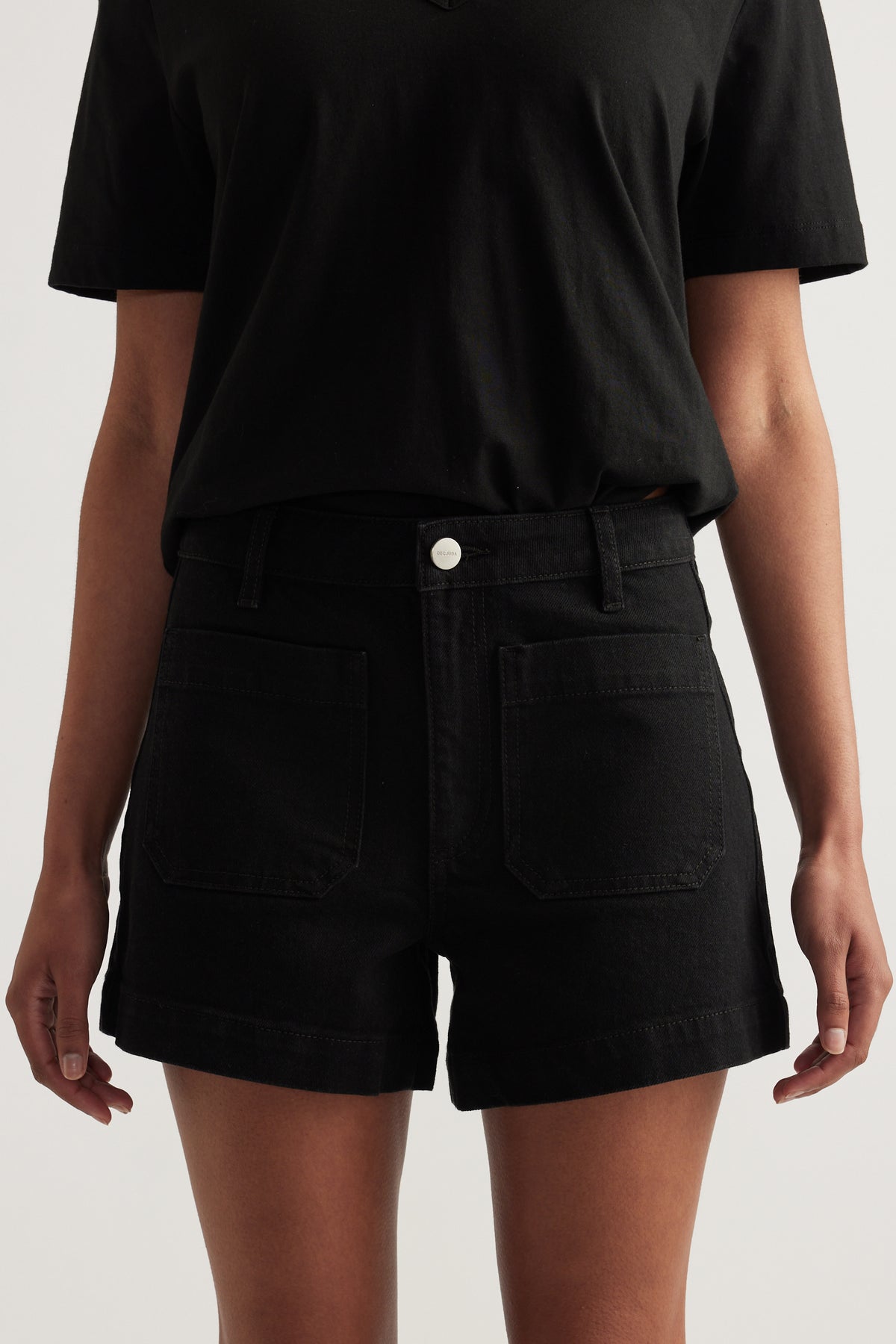 Black high rise denim shorts with front patch pockets, styled with a black tee