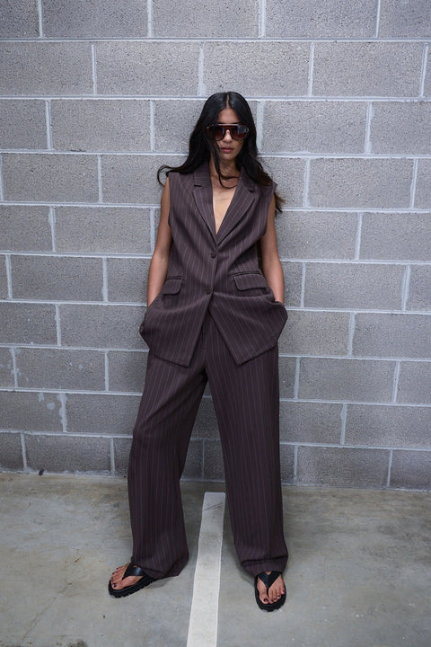 Woman wearing dark pinstripe wide leg pants with a sleeveless tailored vest and black sandals