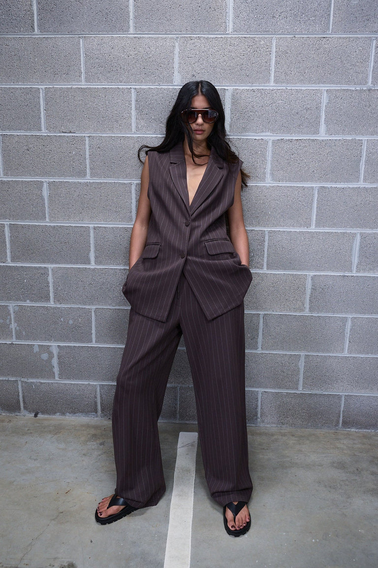 Woman wearing dark pinstripe wide leg pants with a sleeveless tailored vest and black sandals