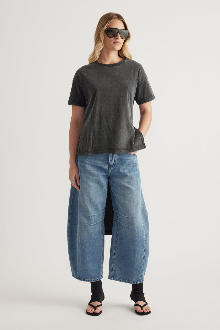 Woman wearing a charcoal high low hem tee with wide leg blue jeans and sandals