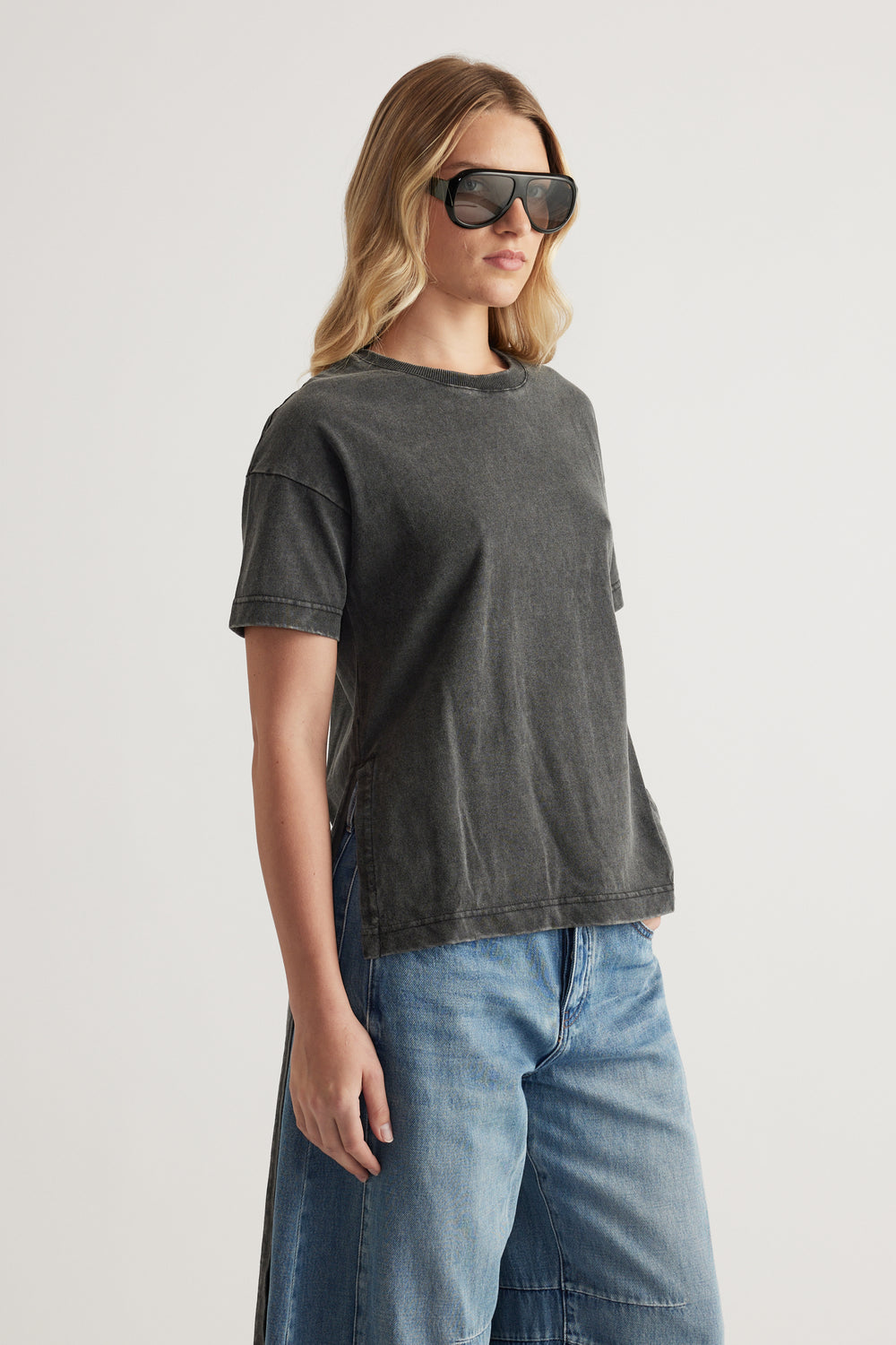Woman wearing a charcoal grey high low hem tee with blue jeans and sunglasses