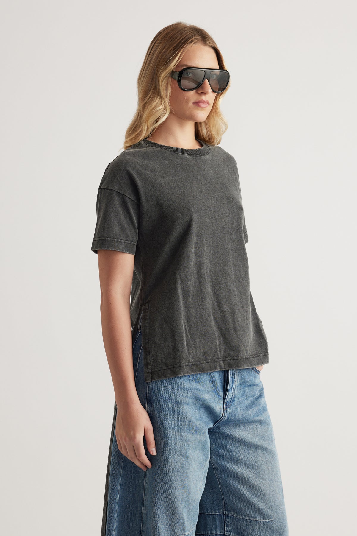 Woman wearing a charcoal grey high low hem tee with blue jeans and sunglasses