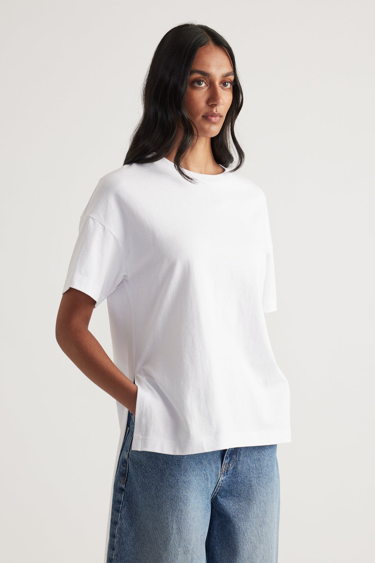 Woman wearing a white relaxed fit tee with a high low hem and blue jeans