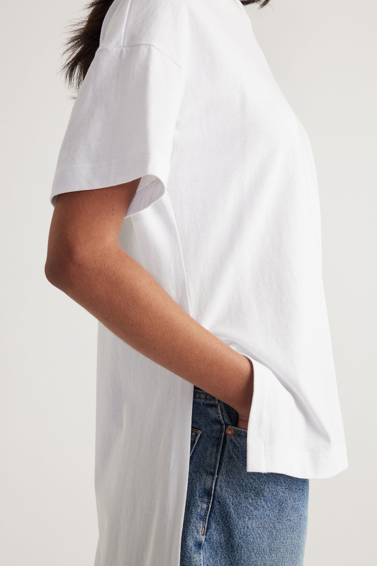 Woman wearing a white relaxed fit tee with a high low hem and blue jeans