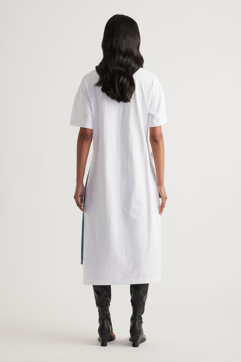 Woman wearing a white longline tee with a high low hem and black knee high boots, viewed from behind