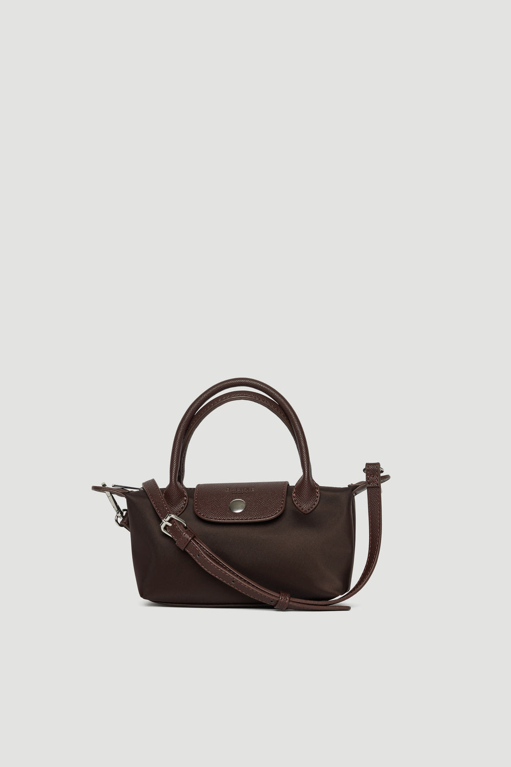 Small dark brown mini crossbody bag with top handles, detachable strap, and silver button closure