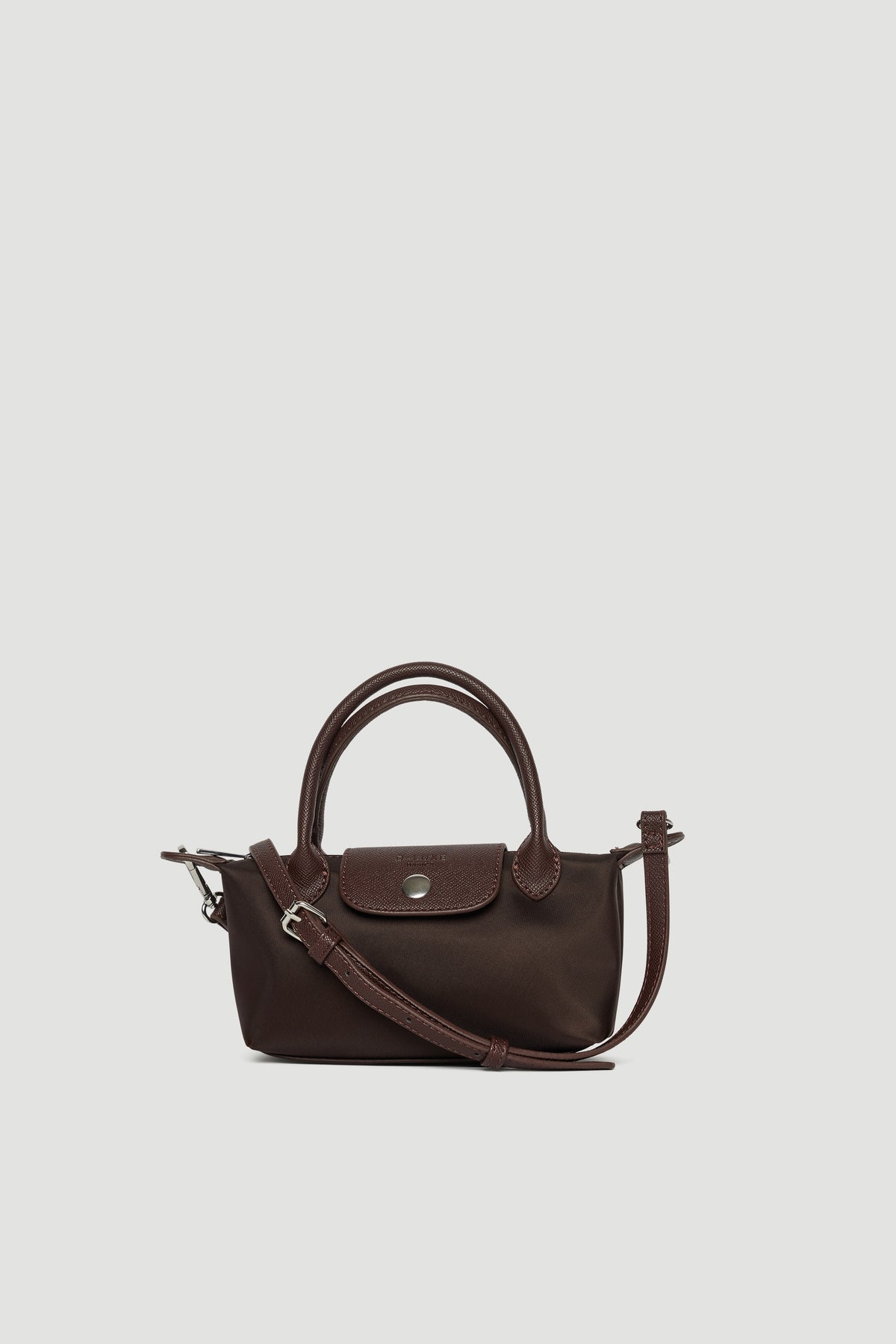 Small dark brown mini crossbody bag with top handles, detachable strap, and silver button closure