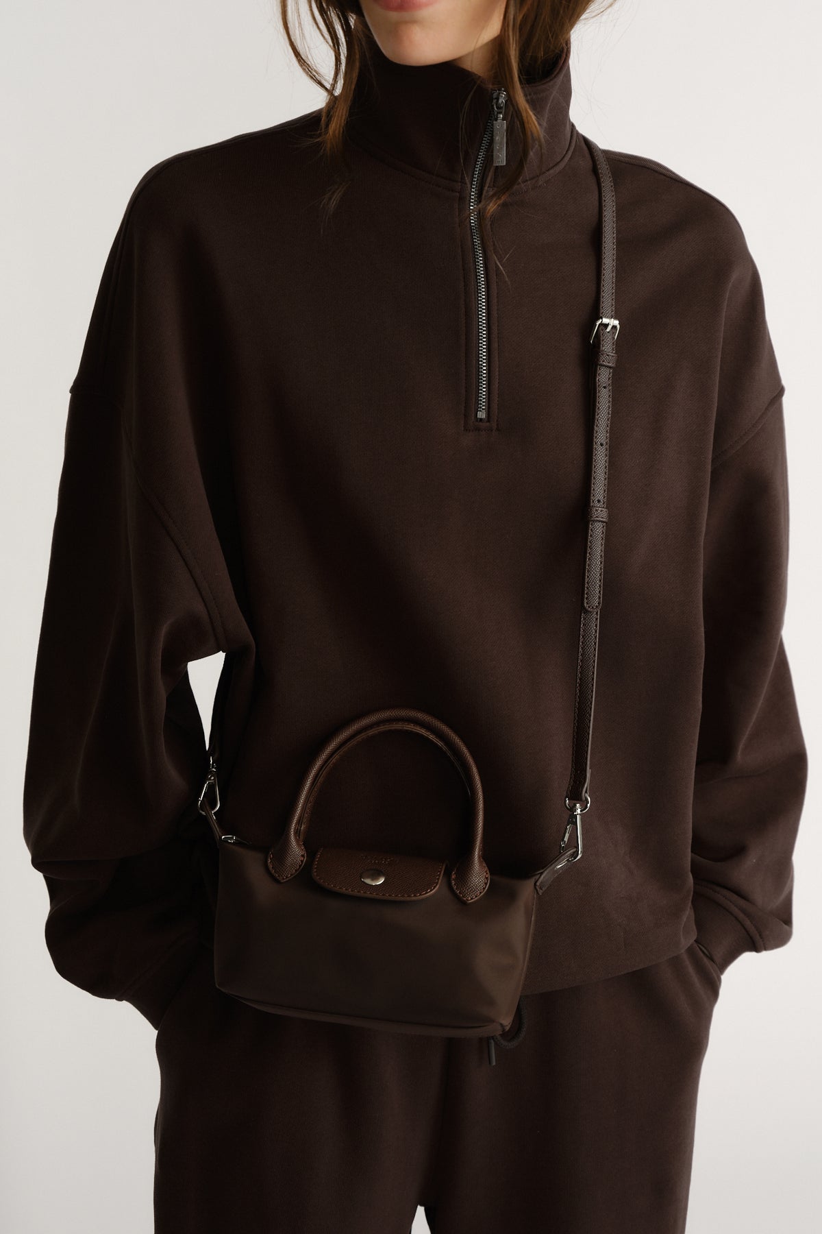Compact chocolate brown mini bag with top handles and adjustable crossbody strap for versatile everyday wear