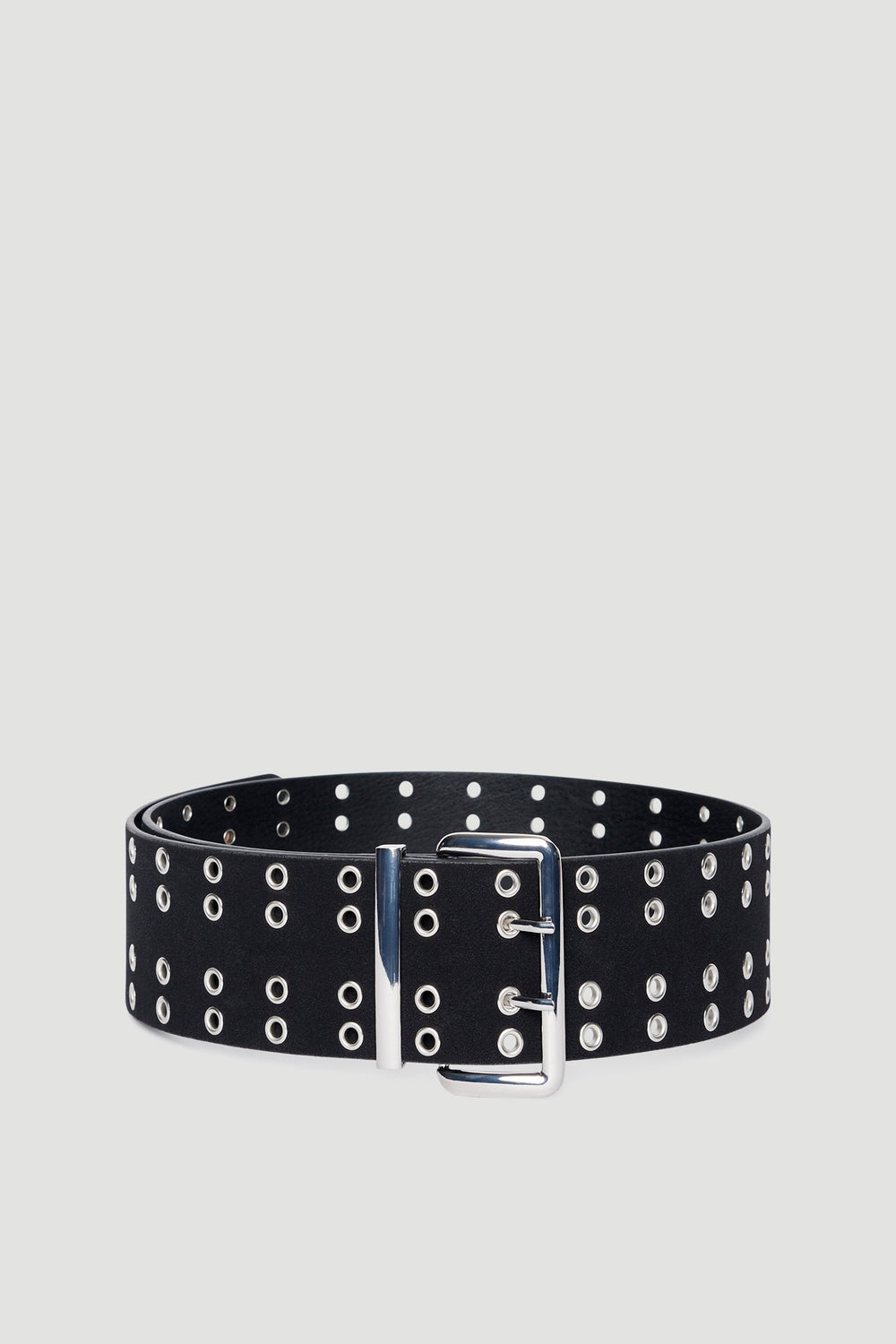 Black faux leather belt with multiple silver eyelets and a large silver buckle and keeper on neutral background