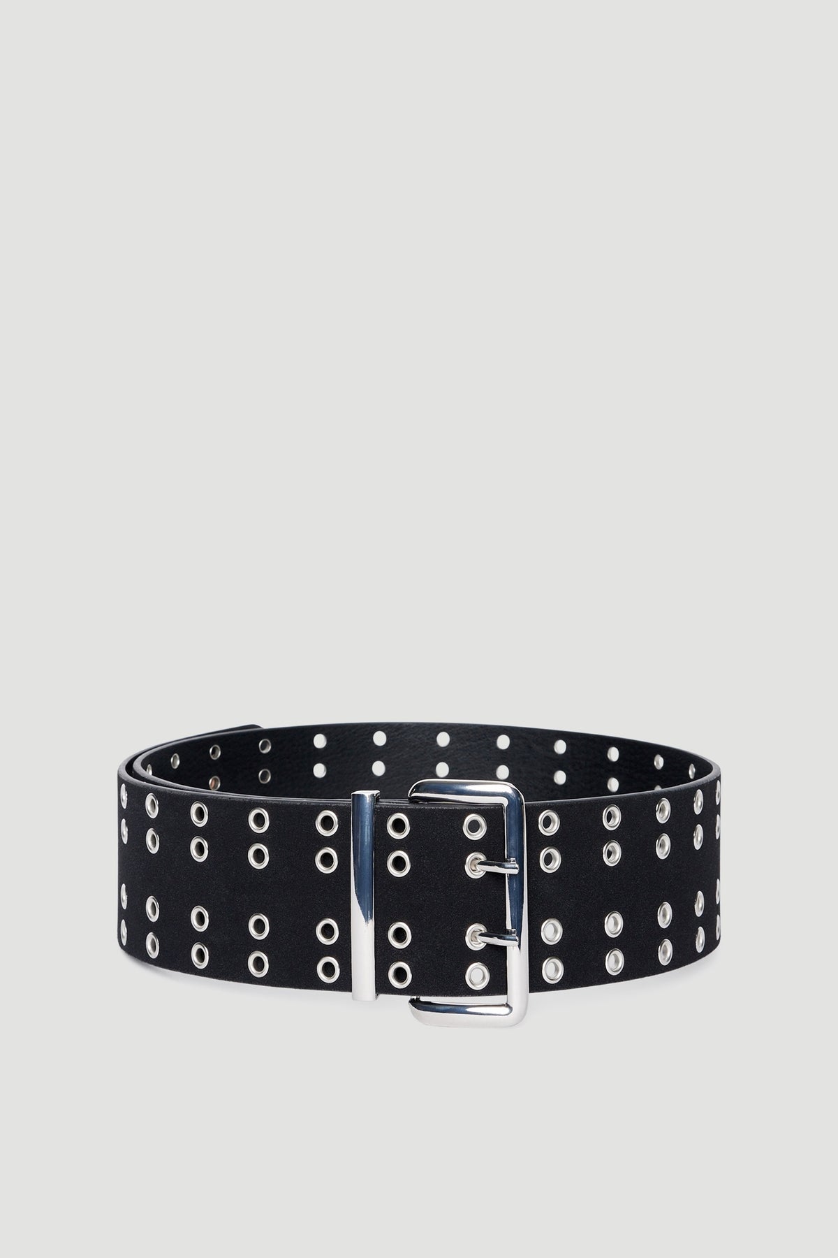 Black faux leather belt with multiple silver eyelets and a large silver buckle and keeper on neutral background
