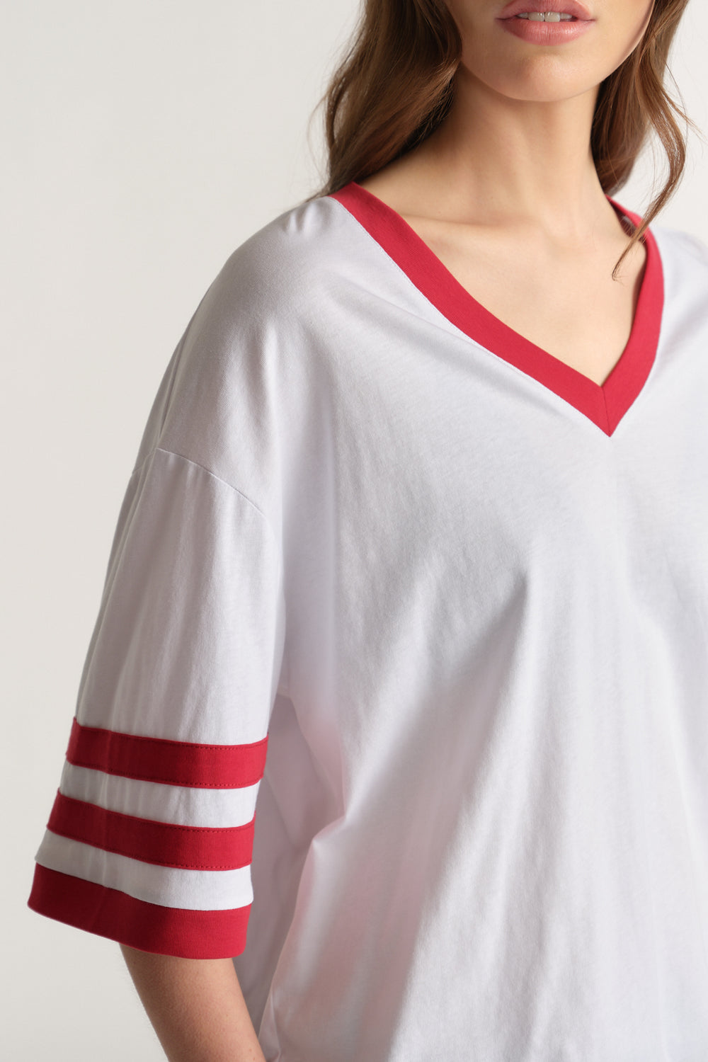 Woman wearing a white oversized V-neck tee with red trim and striped mid-length sleeves