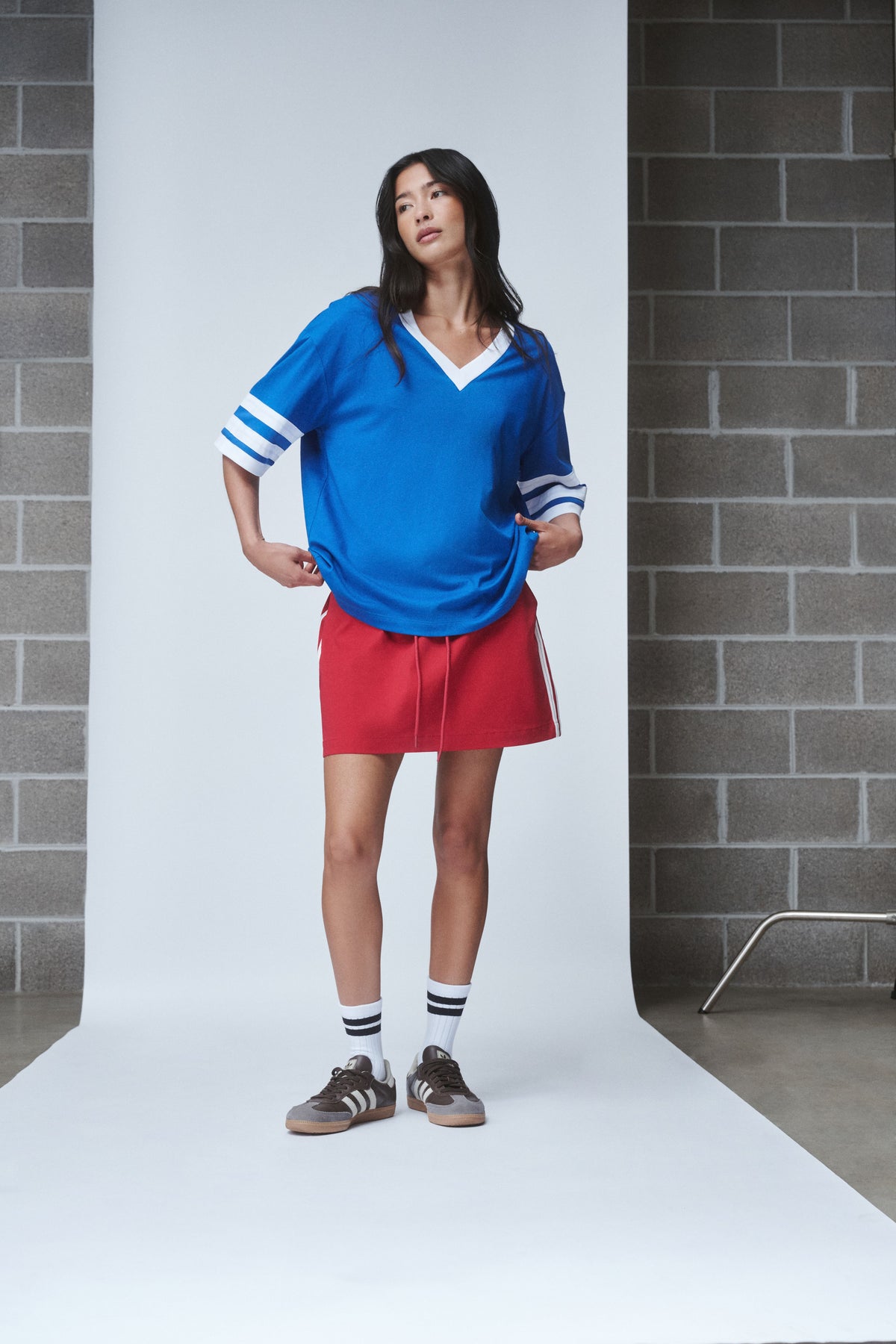Woman wearing a blue V-neck tee with striped sleeves red shorts and sneakers