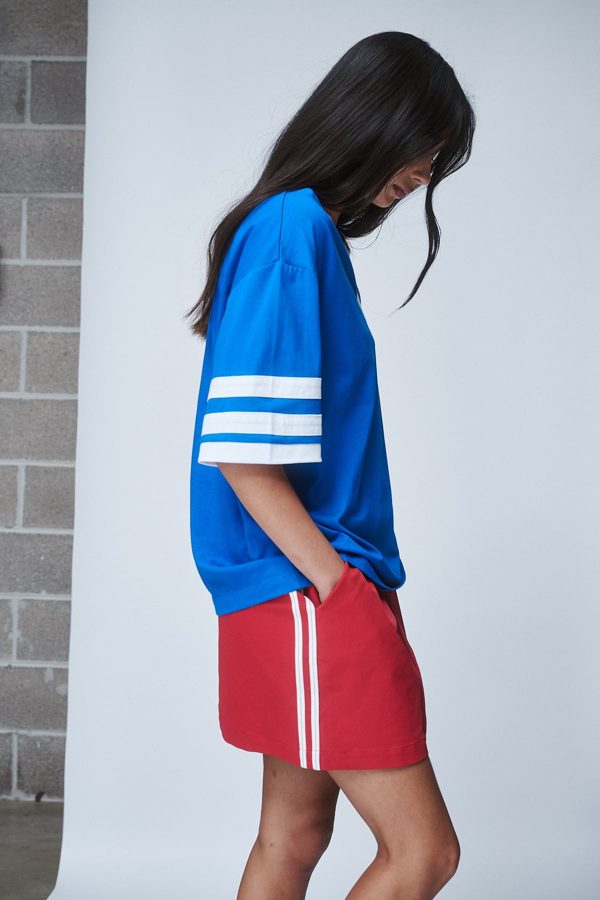 Woman wearing an oversized blue tee with white sleeve stripes and red shorts