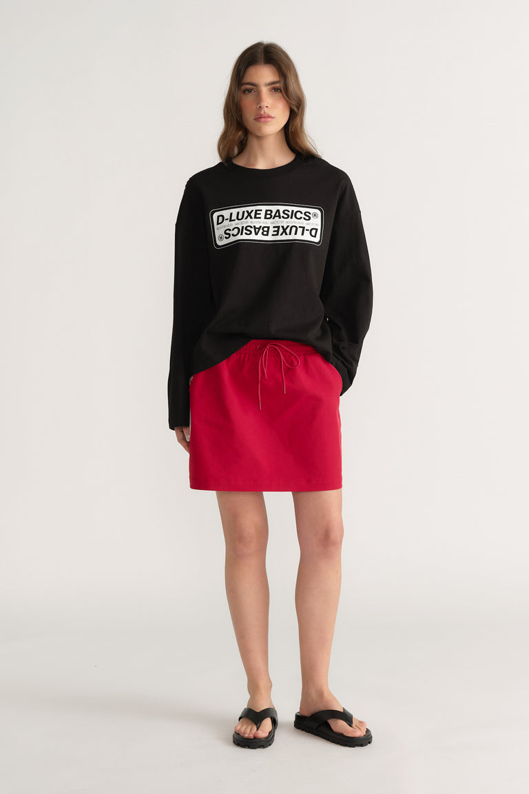 Woman wearing a bright red elastic waist mini skirt with a black sweatshirt and black sandals