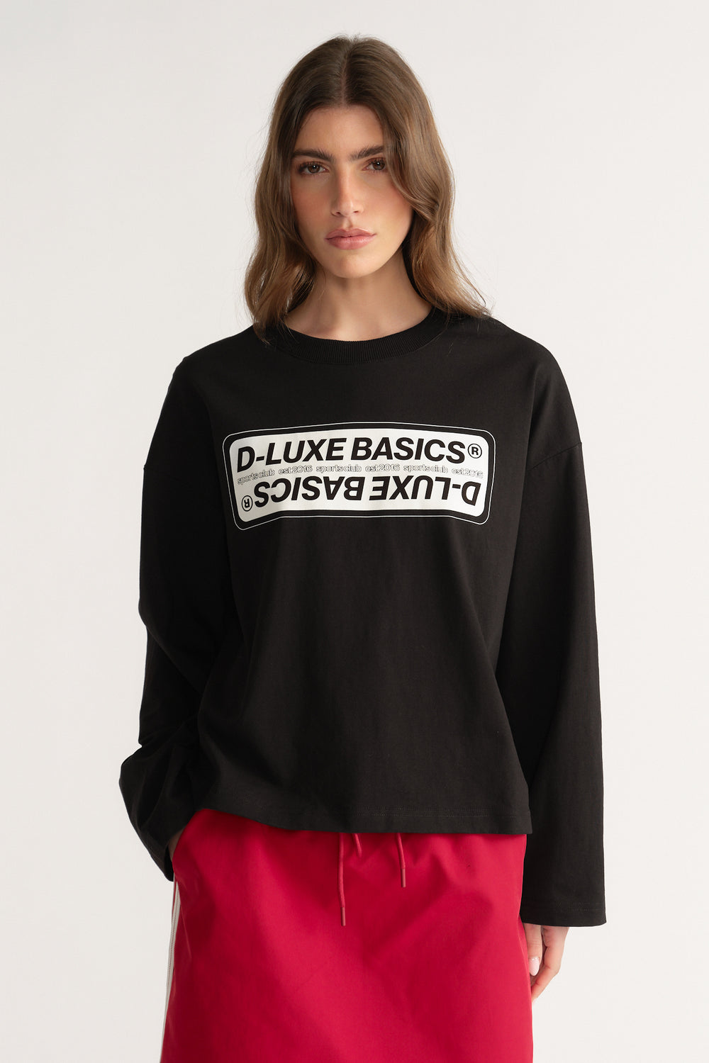 Woman wearing a black oversized D-Luxe graphic long sleeve tee with bright pink drawstring pants