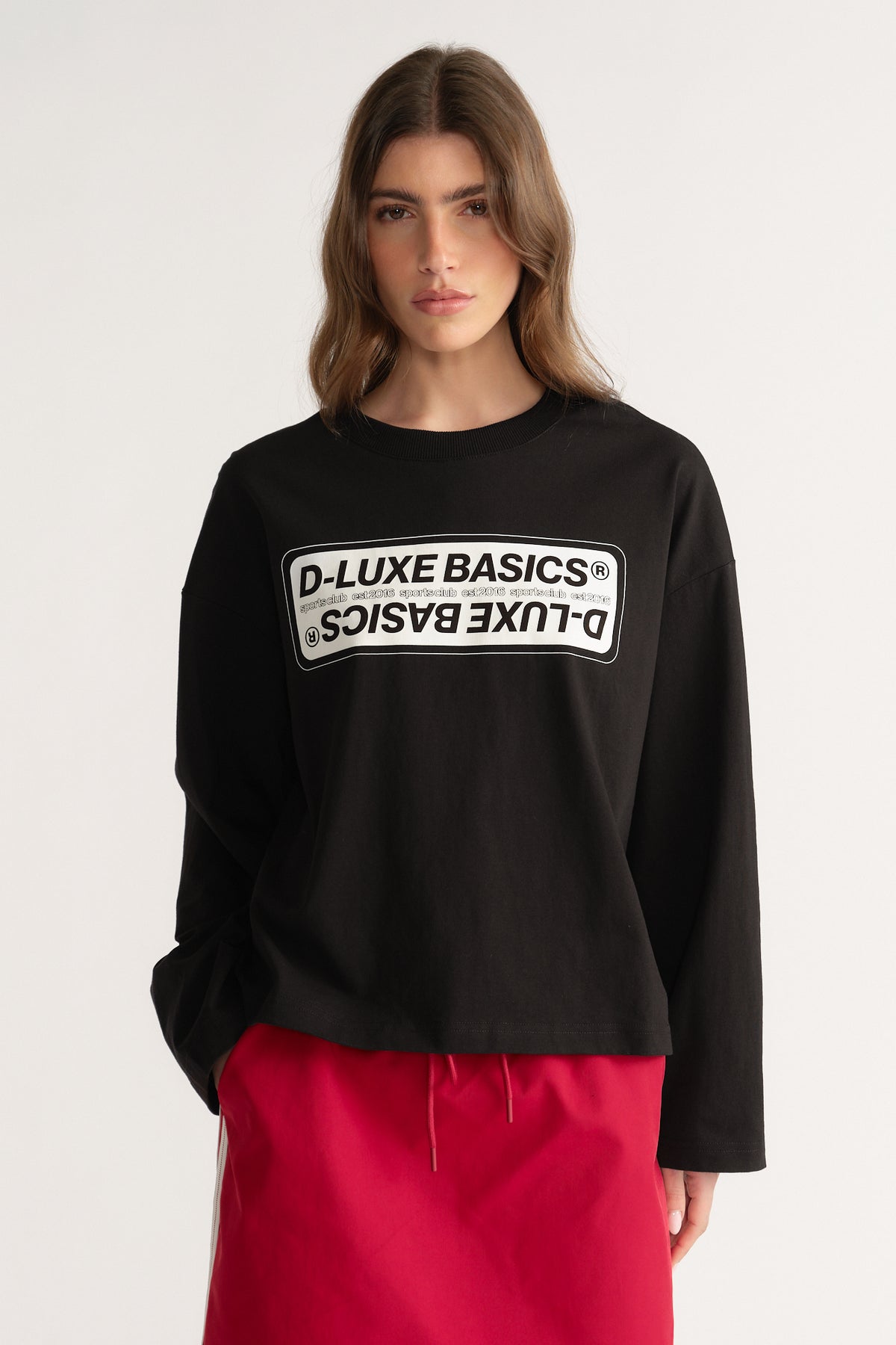 Woman wearing a black oversized D-Luxe graphic long sleeve tee with bright pink drawstring pants