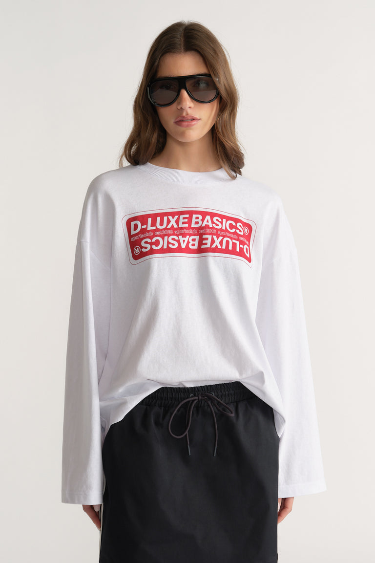 Woman wearing an oversized white D-Luxe graphic long sleeve tee with black drawstring pants and sunglasses