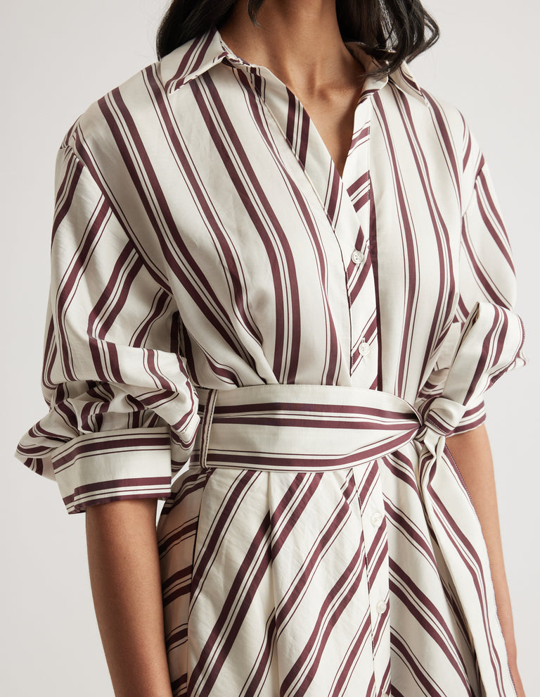 Woman wearing a cream and burgundy striped collared shirt dress with a tied waist and rolled sleeves
