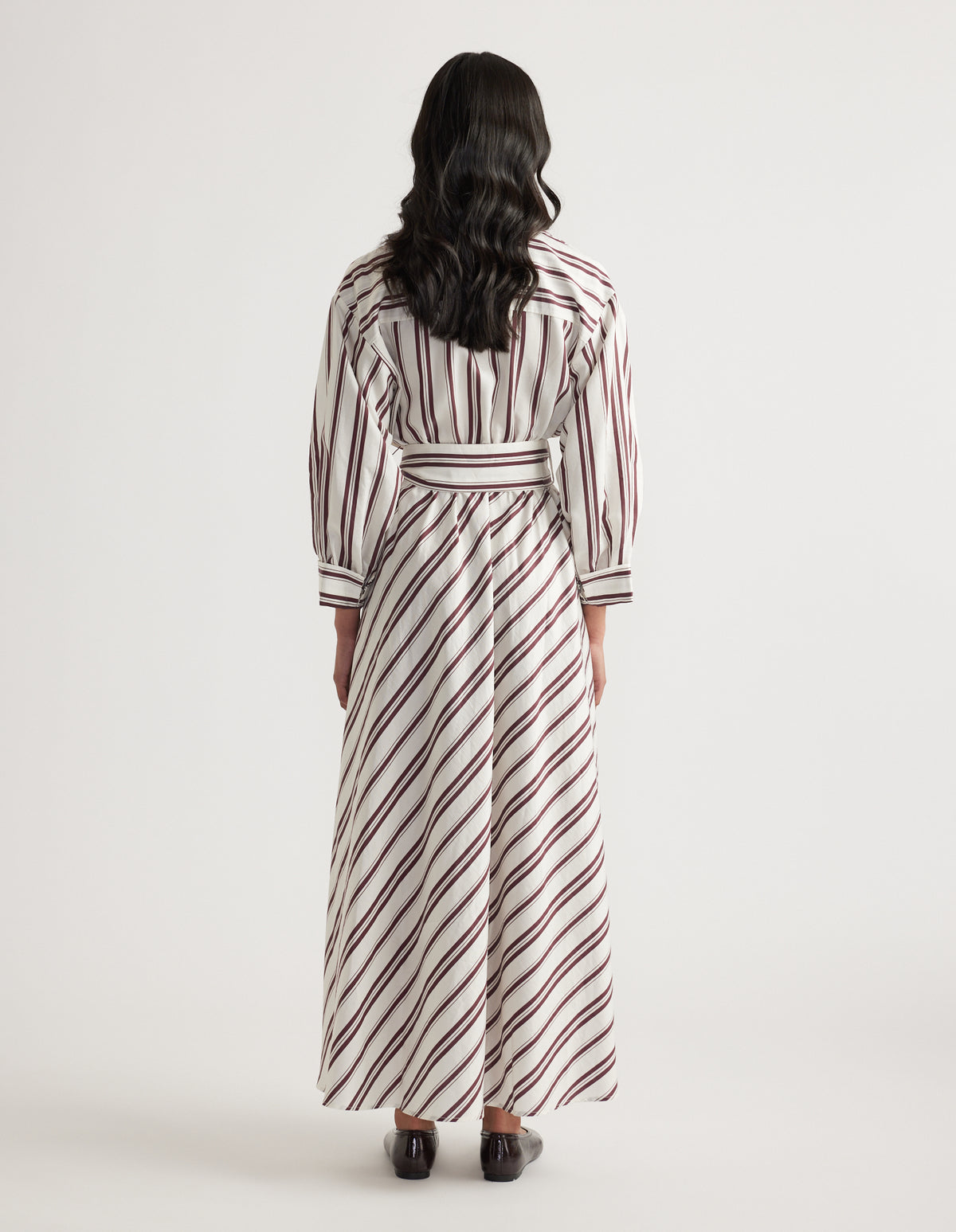 Woman viewed from behind in a striped long sleeve shirt dress with a collared neckline and tied waist