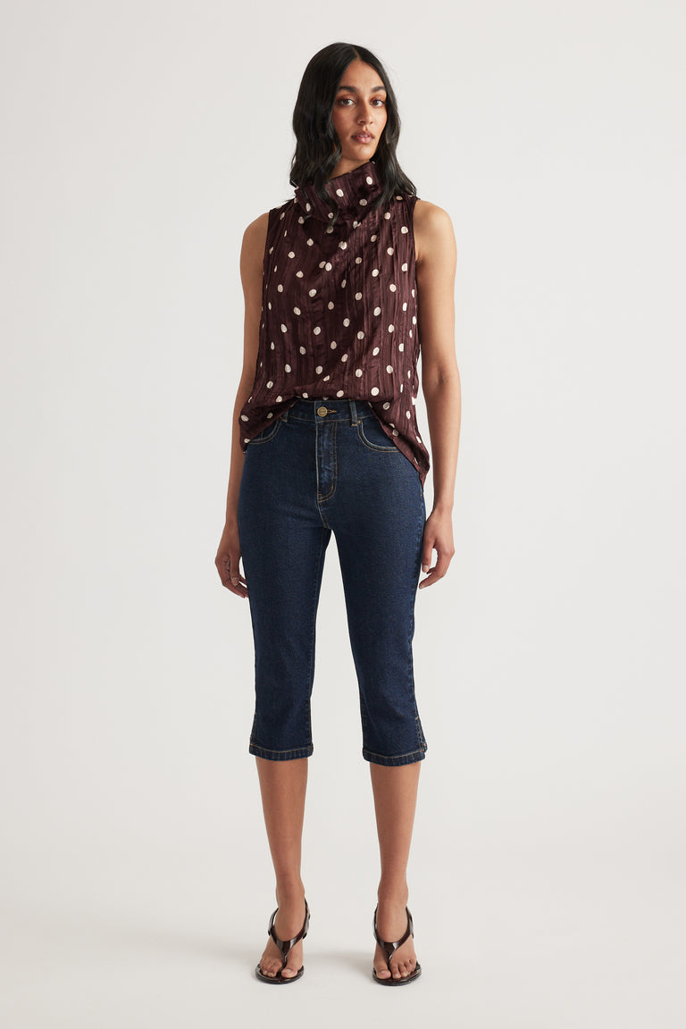 Woman wearing a brown sleeveless cowl neck textured top with cropped dark jeans and strappy heels