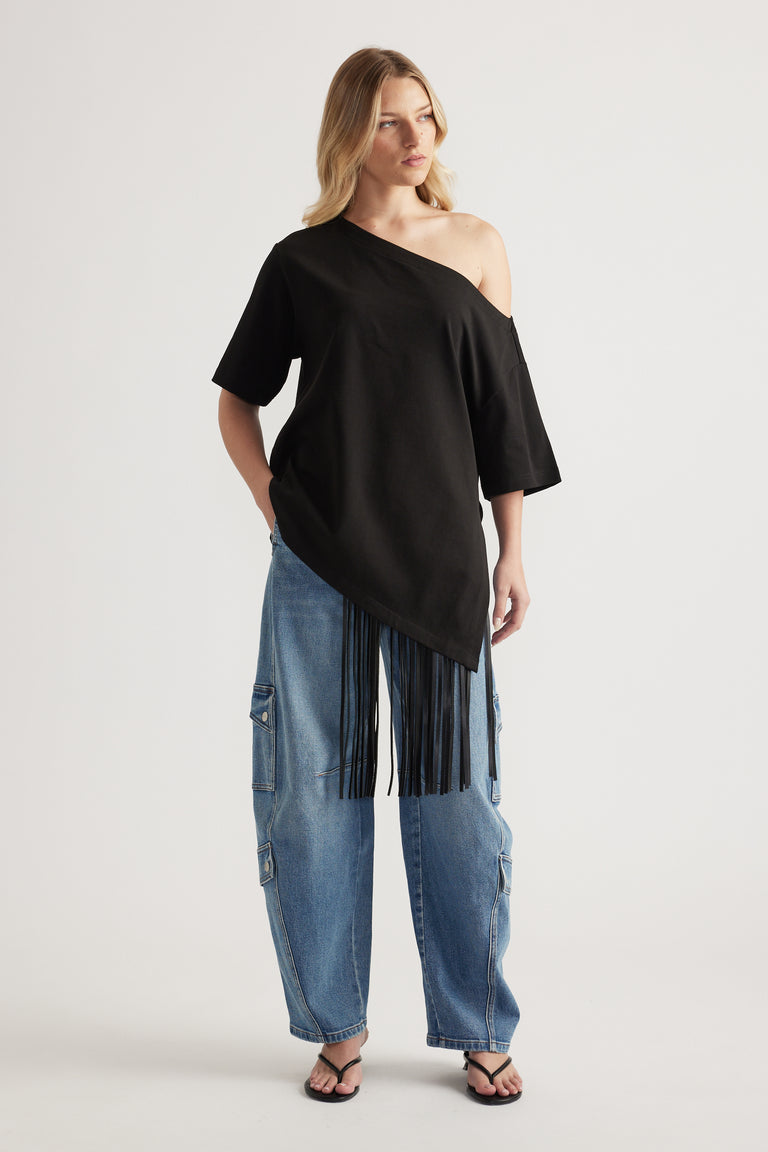 Woman wearing blue high rise barrel leg cargo jeans with a black off shoulder top and flat sandals