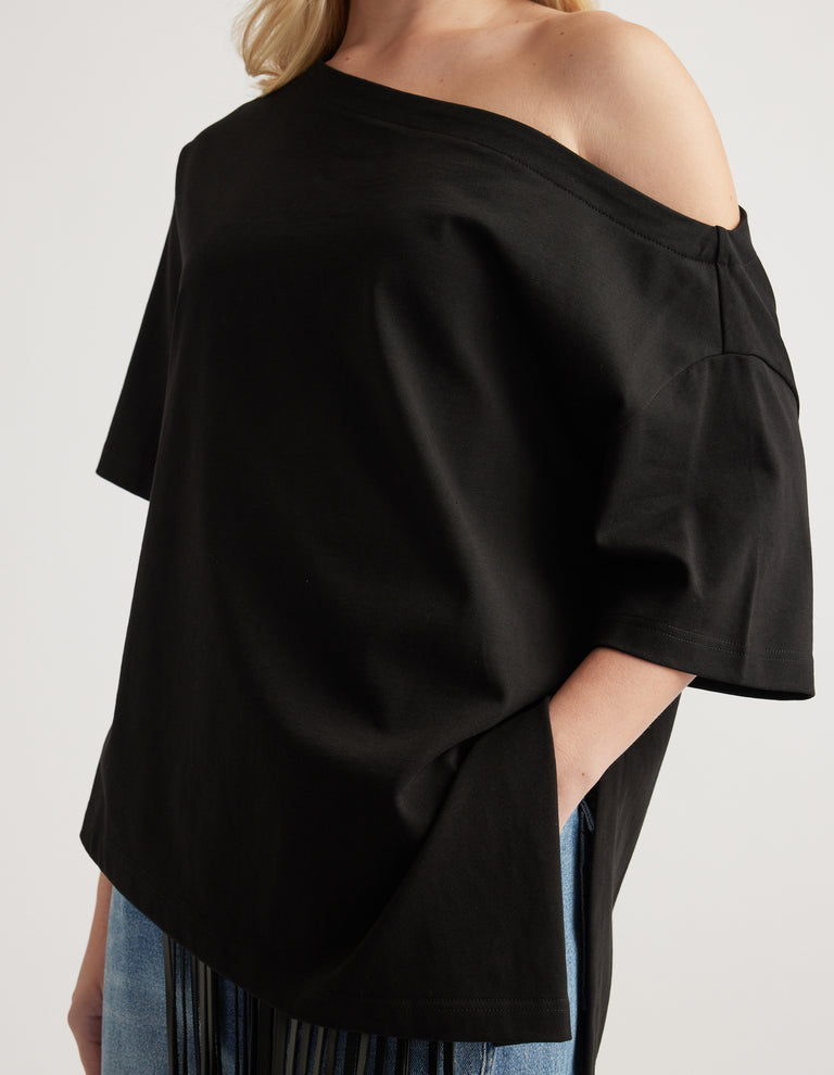Woman wearing a relaxed black short sleeve tee with an asymmetric neckline and hem