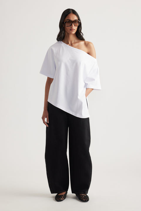 Woman wearing a white relaxed fit tee with asymmetric neckline and hem, black wide leg pants and sunglasses