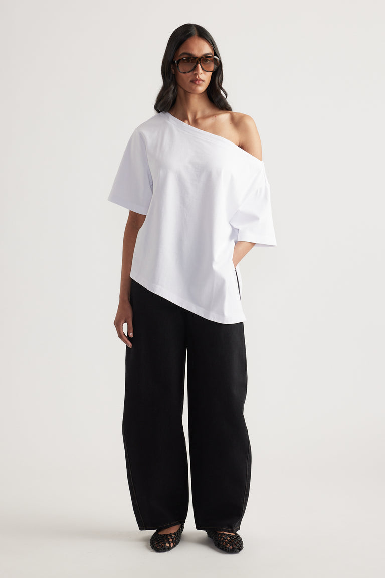 Woman wearing a white relaxed fit tee with asymmetric neckline and hem, black wide leg pants and sunglasses