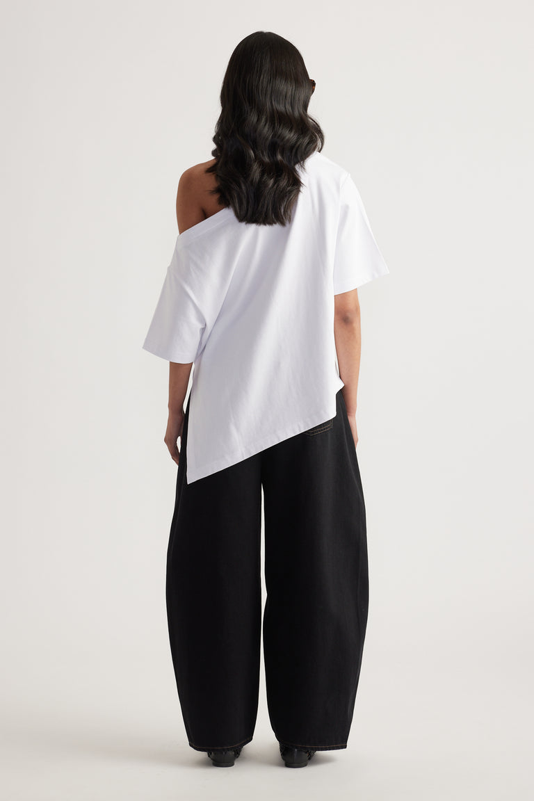 Woman seen from behind wearing a white asymmetric neckline tee with uneven hem and black wide leg pants