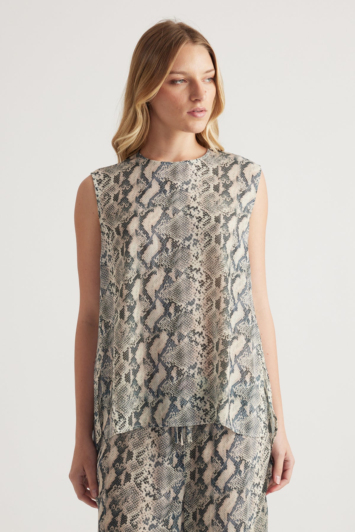 Woman wearing a high neck sleeveless snakeskin print tank top with matching pants
