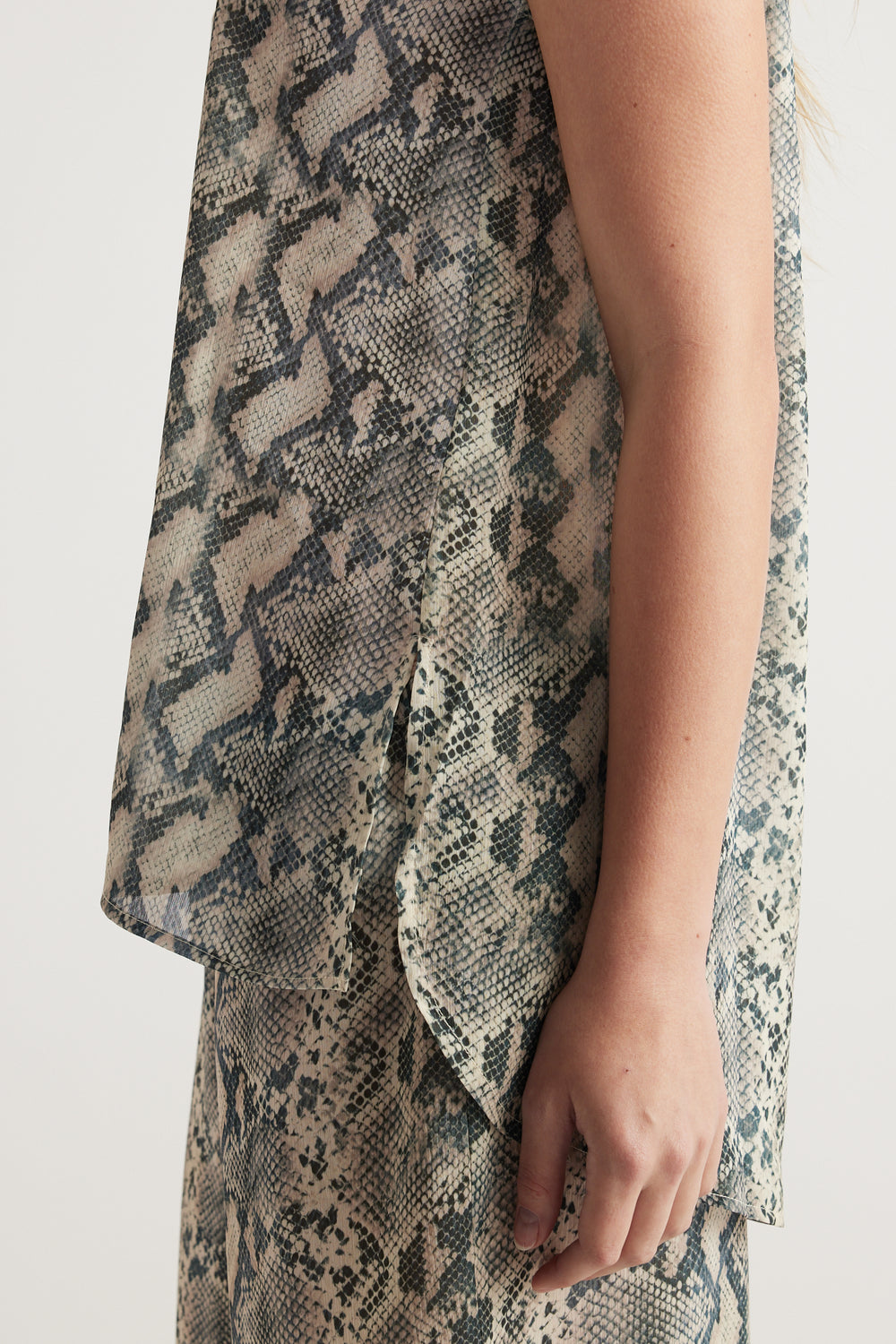 Woman wearing a snakeskin print sleeveless tank top with a draped side panel