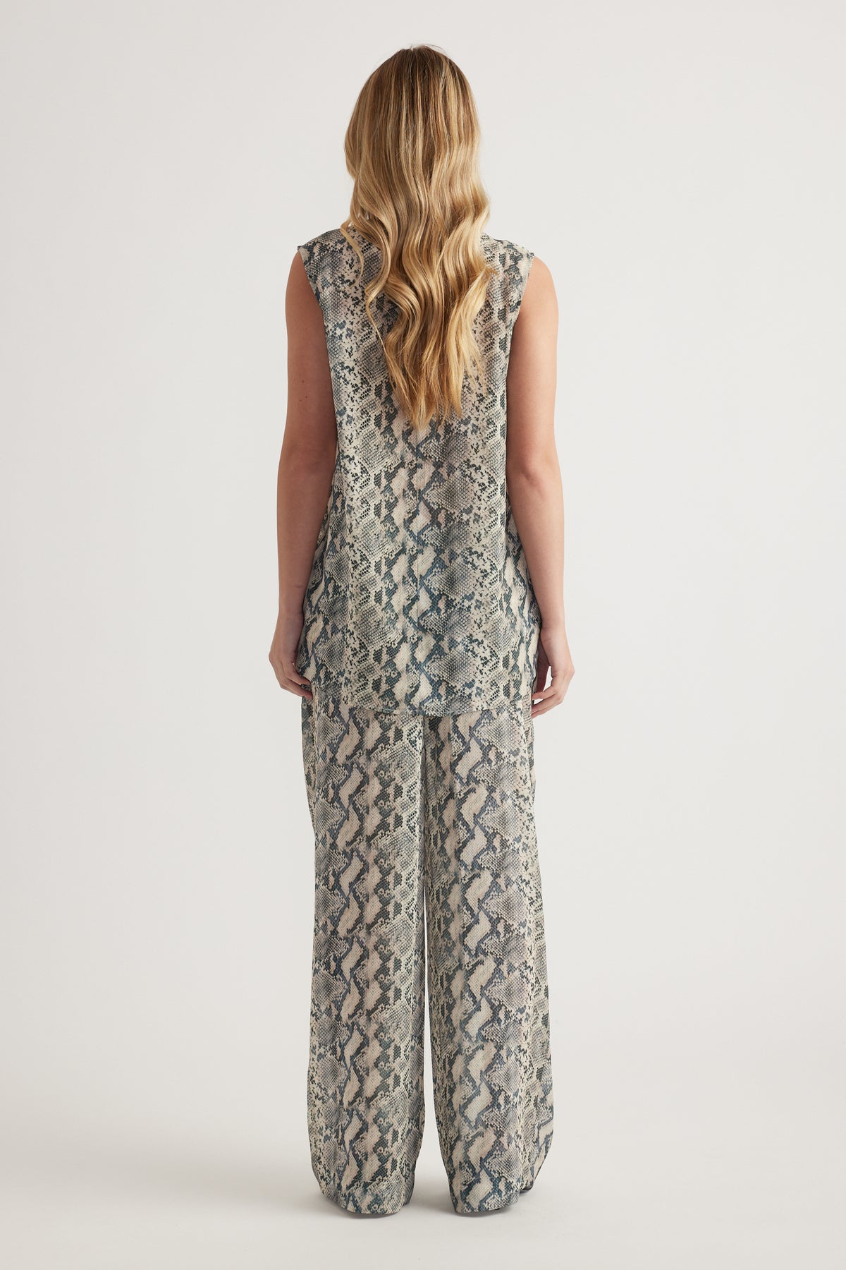Woman wearing a sleeveless snakeskin print high neck tank top, viewed from behind