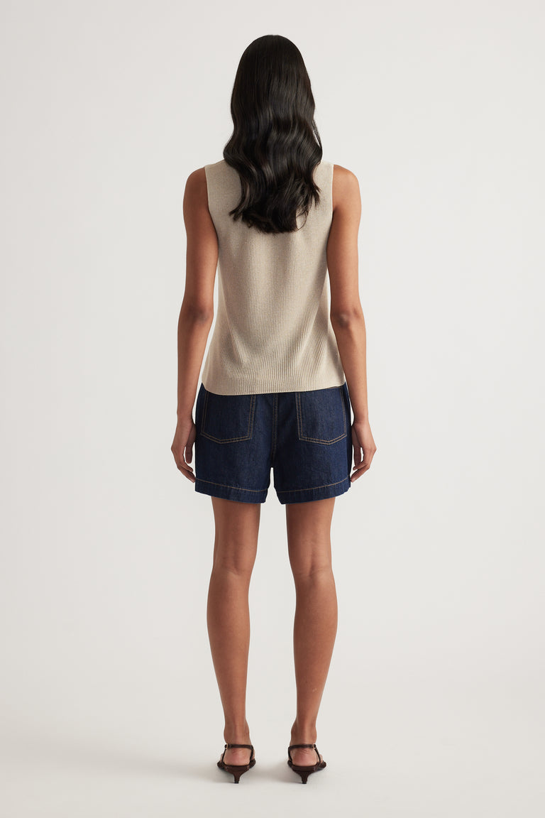 Back view of a model wearing a metallic knit tank with dark denim shorts