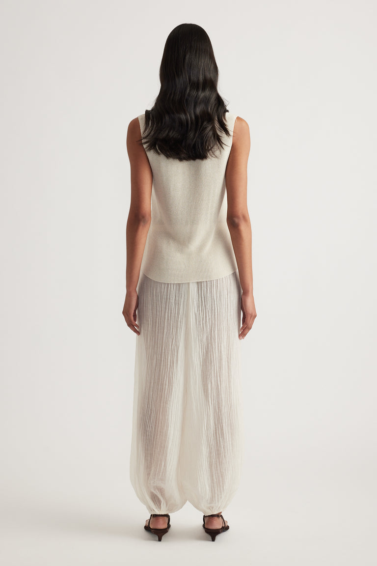 Back view of a model wearing a beige metallic knit tank with flowing wide-leg pants