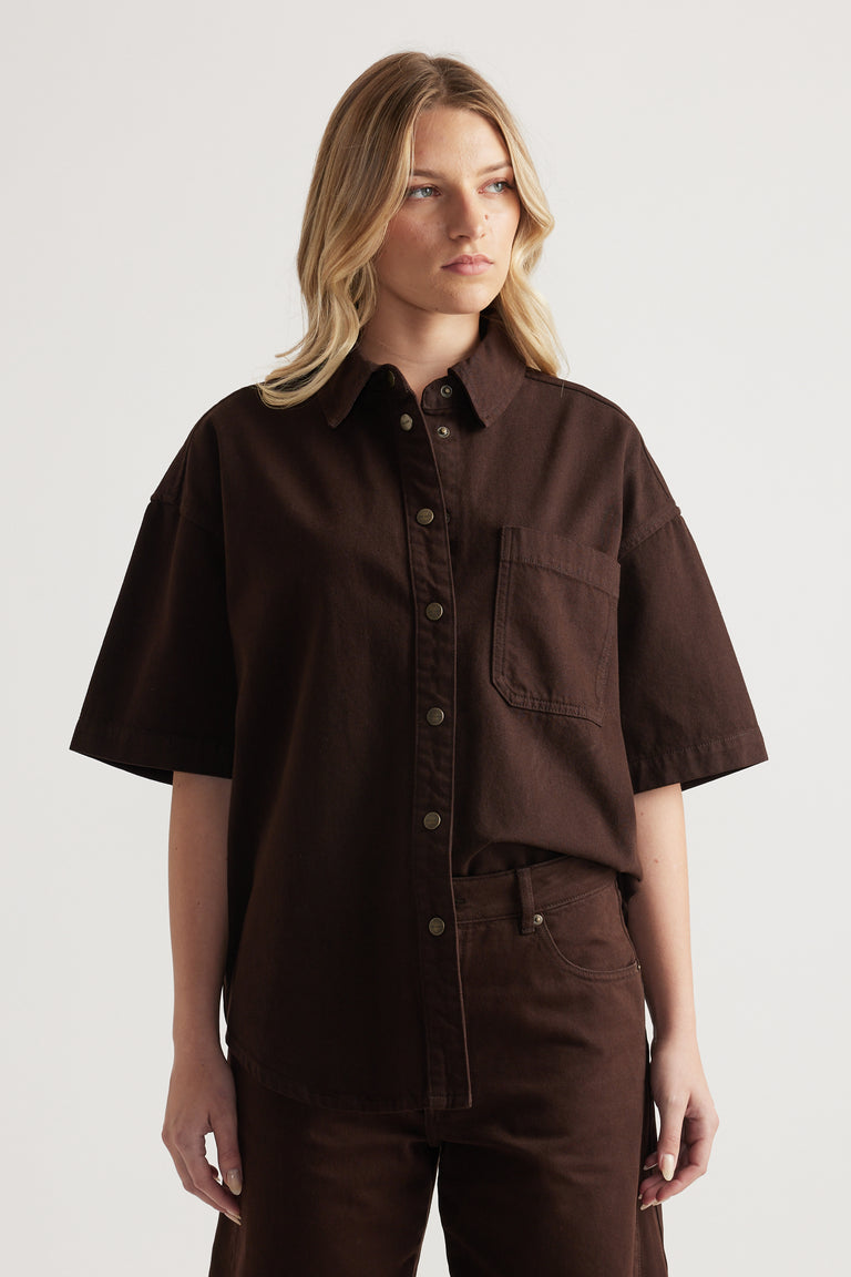 Woman wearing an oversized brown denim shirt with short sleeves and matching jeans