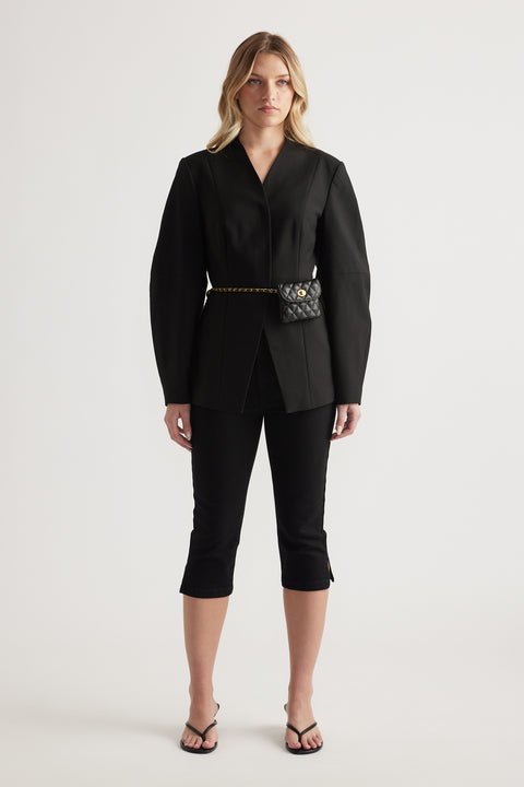 Woman wearing a black blazer with black denim capri pants and strappy sandals