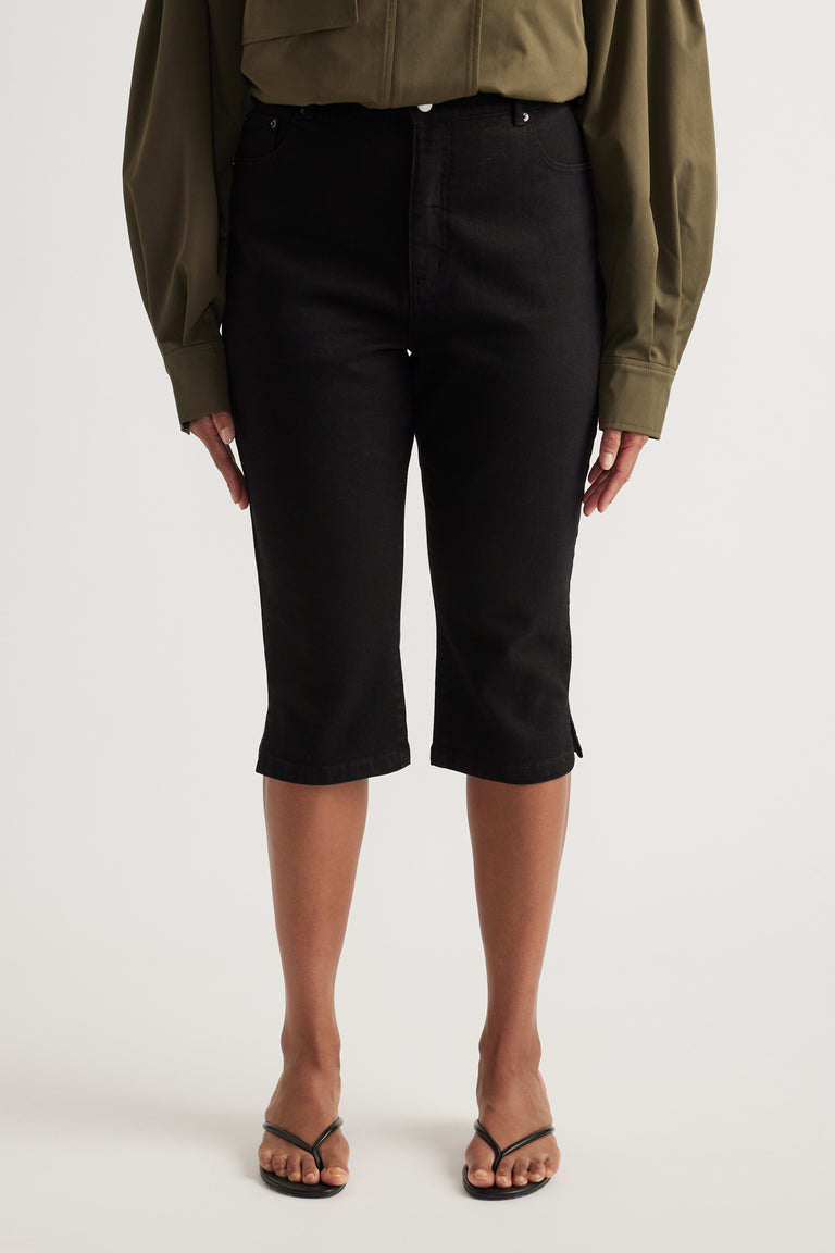 Woman wearing black high-rise denim capris with an olive shirt and strappy sandals