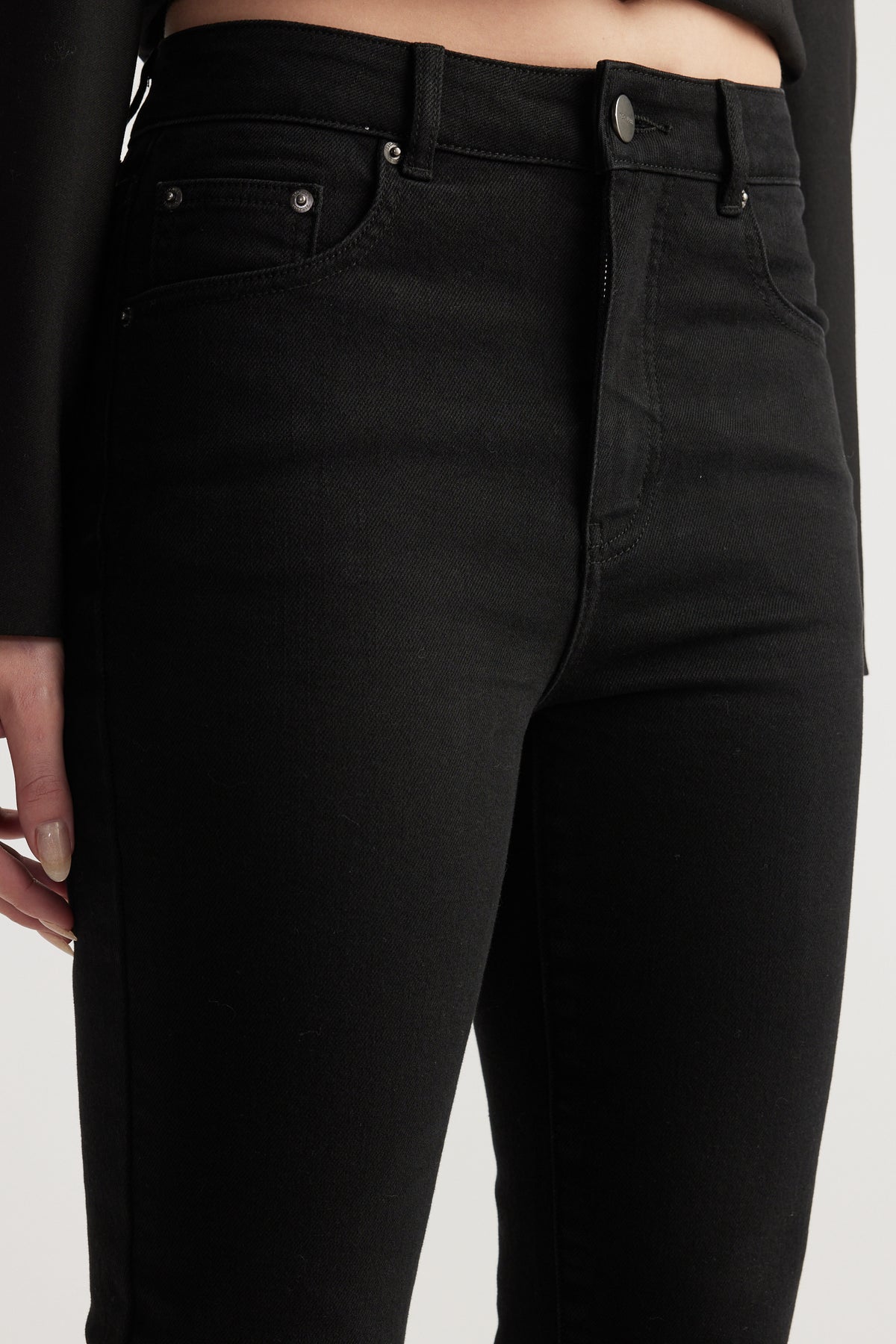 Close up of a woman wearing high rise black stretch denim capris with a slim fit