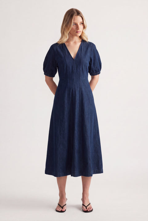 Woman wearing a dark blue panelled denim midi dress with puff sleeves and black sandals