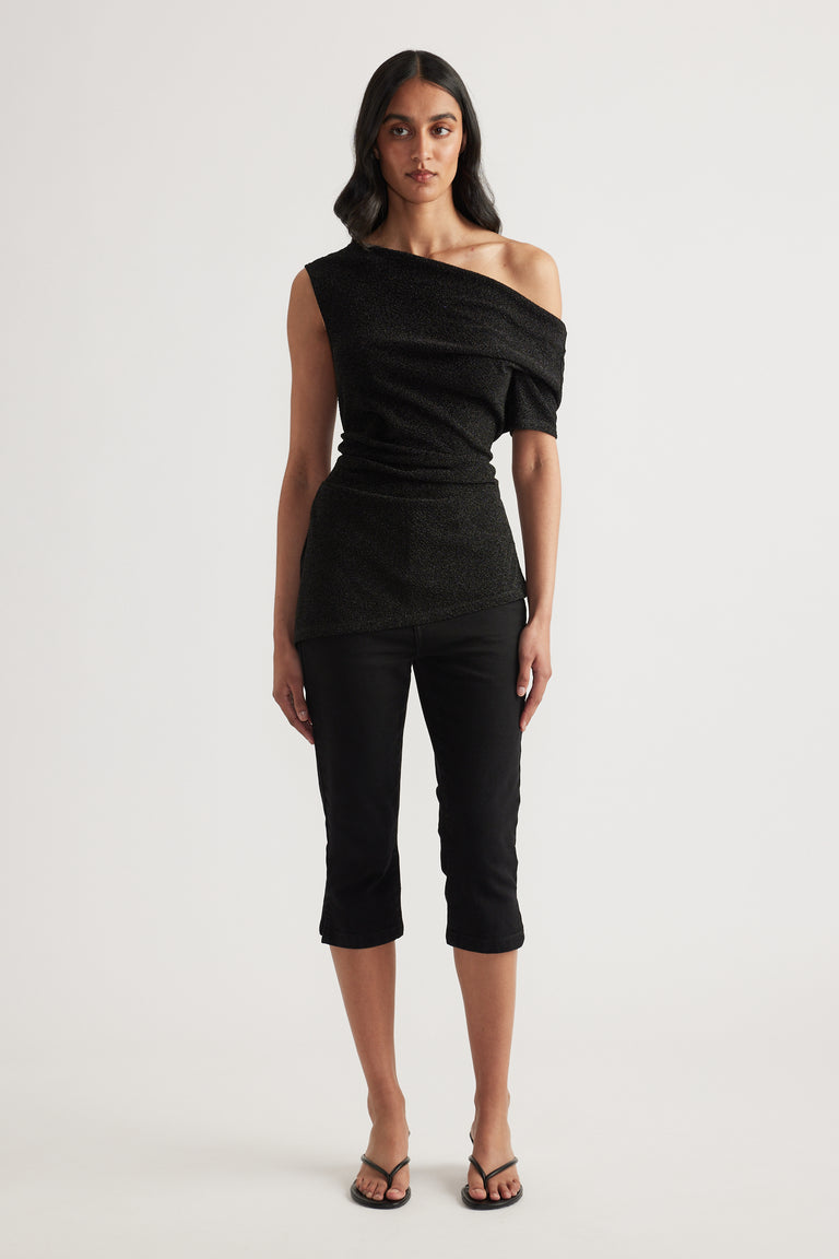 Woman wearing a black off shoulder top with an asymmetric neckline, cropped pants and strappy sandals