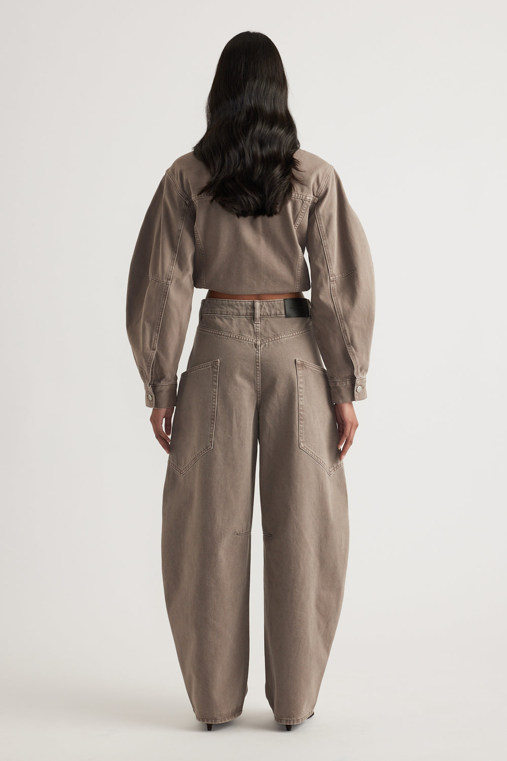 Woman wearing taupe cargo barrel leg jeans with back pockets and a matching cropped denim jacket